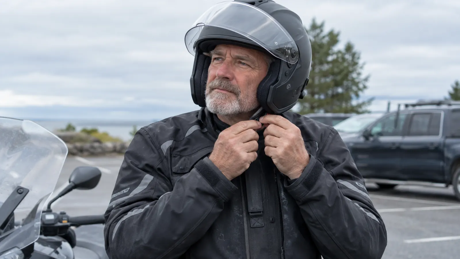 A rider's hands adjusting the strap of a full-face helmet before a ride